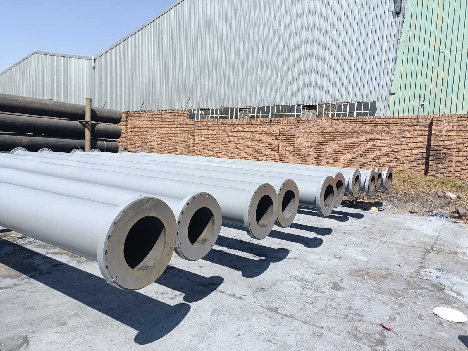 Coated flanged steel pipes lined up outdoors ready for dispatch from Wetpipe
