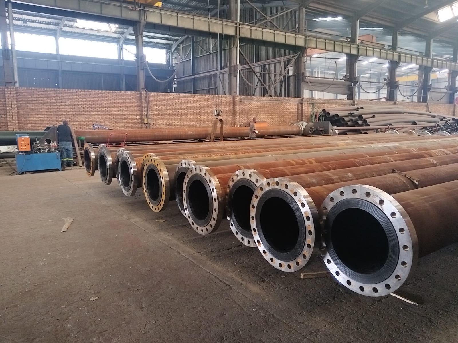 HDPE-lined flanged steel pipe spools lined up on the Wetpipe fabrication floor